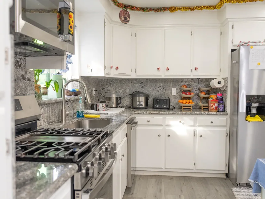 Bright residential kitchen with white cabinets, granite countertops, stainless steel appliances, and holiday decorations